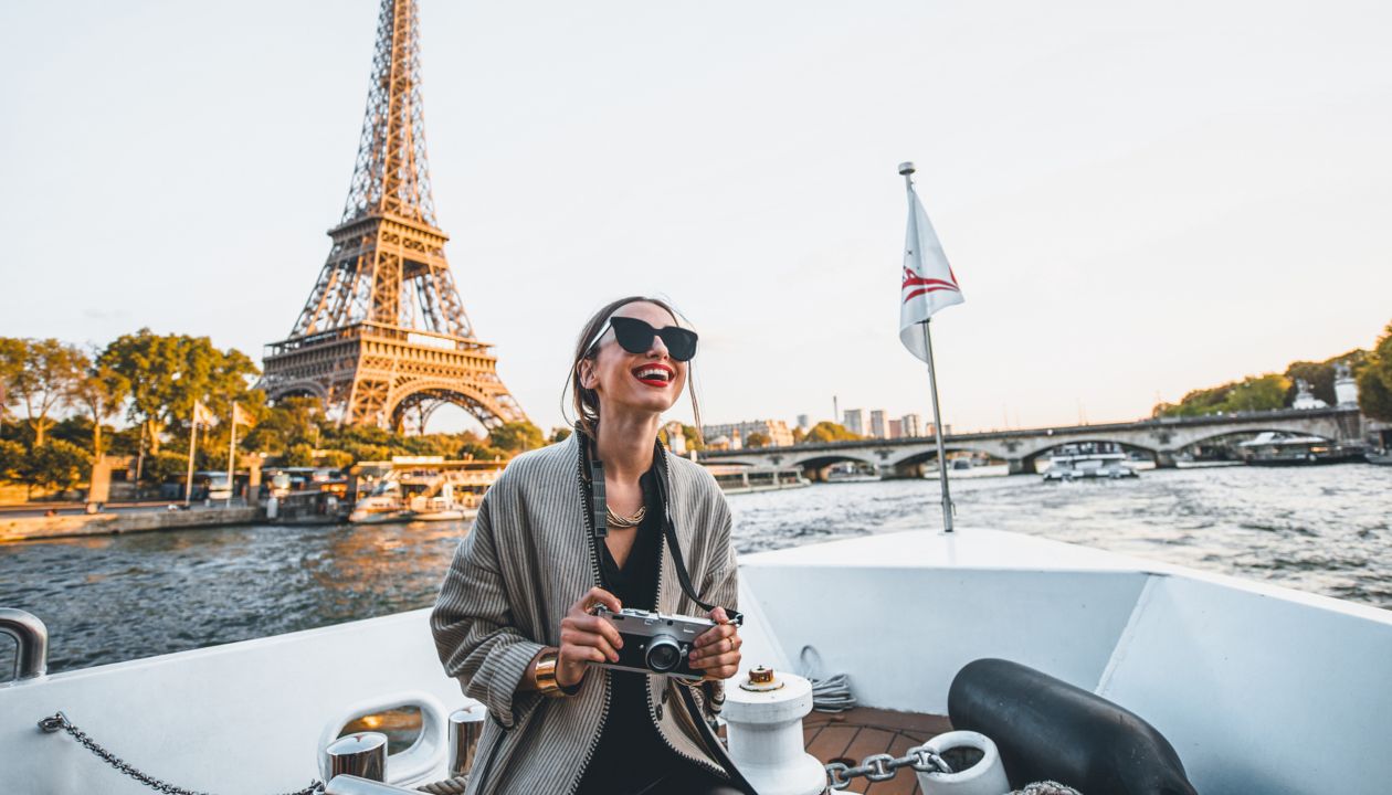 Young woman enjoying beautiful landscape view on the riverside with Eiffel tower from the boat during the sunset in Paris