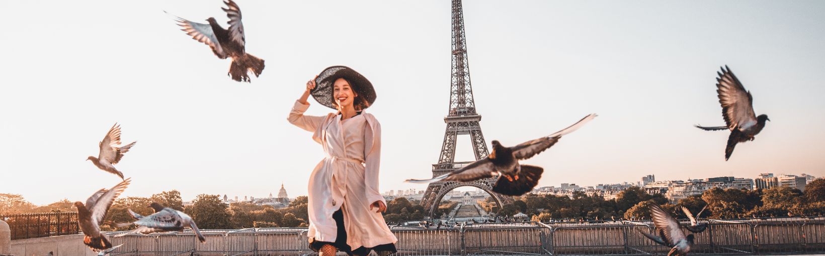 Woman running on the famous square dispersing pigeons with great view on the Eiffel tower early in the morning in Paris.