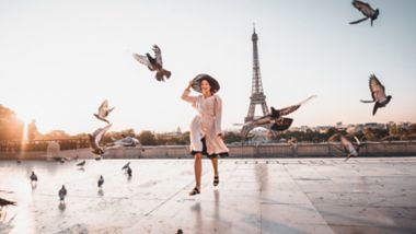 Woman running on the famous square dispersing pigeons with great view on the Eiffel tower early in the morning in Paris