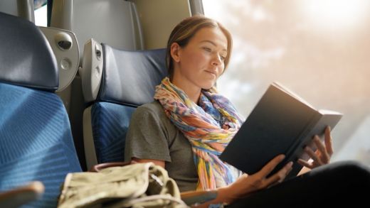 Relaxed young woman reading on the train                               