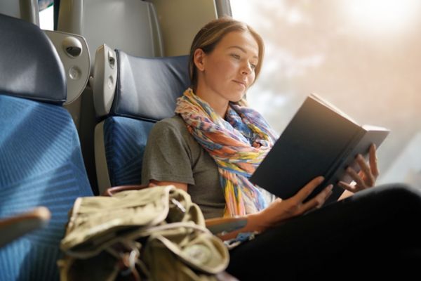 Relaxed young woman reading on the train                               