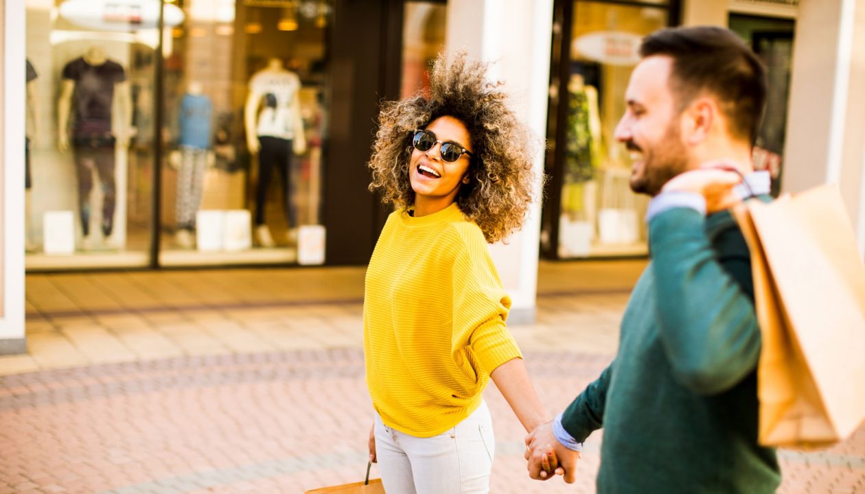 Lovely young multiethnic couple with bags in the shopping