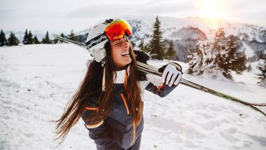 Portrait of beautiful woman with ski and ski suit in winter mountain