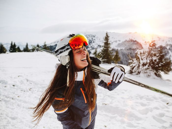 Portrait of beautiful woman with ski and ski suit in winter mountain