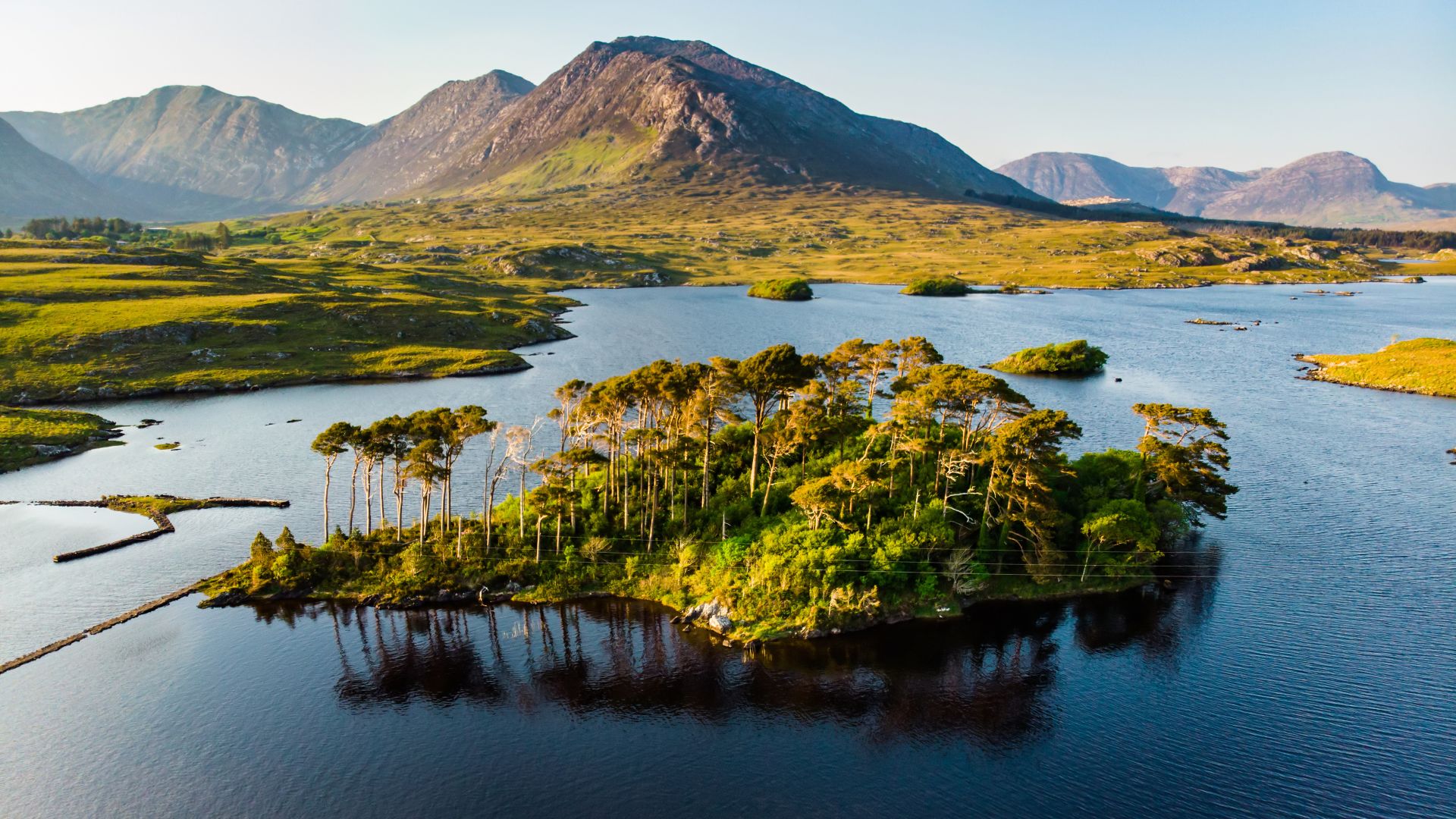 Aerial view of Twelve Pines Island, standing on a gorgeous background formed by the sharp peaks of a mountain range called Twelve Pins or Twelve Bens, Connemara, County Galway, Ireland