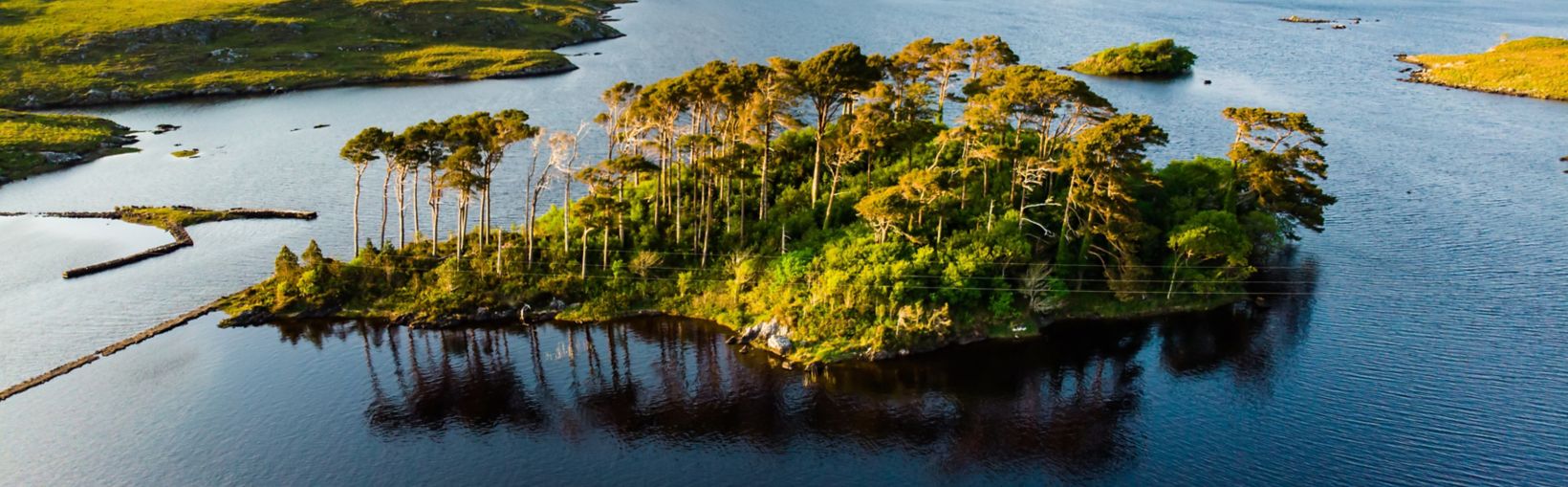 Aerial view of Twelve Pines Island, standing on a gorgeous background formed by the sharp peaks of a mountain range called Twelve Pins or Twelve Bens, Connemara, County Galway, Ireland