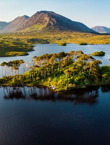 Aerial view of Twelve Pines Island, standing on a gorgeous background formed by the sharp peaks of a mountain range called Twelve Pins or Twelve Bens, Connemara, County Galway, Ireland