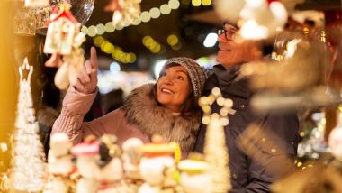 shopping, winter holidays and people concept - happy senior couple at christmas market souvenir shop on town hall square in tallinn, estonia