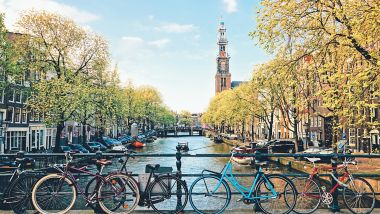 Bicycles lining a bridge over the canals of Amsterdam with church in background. Late day light. Netherlands.