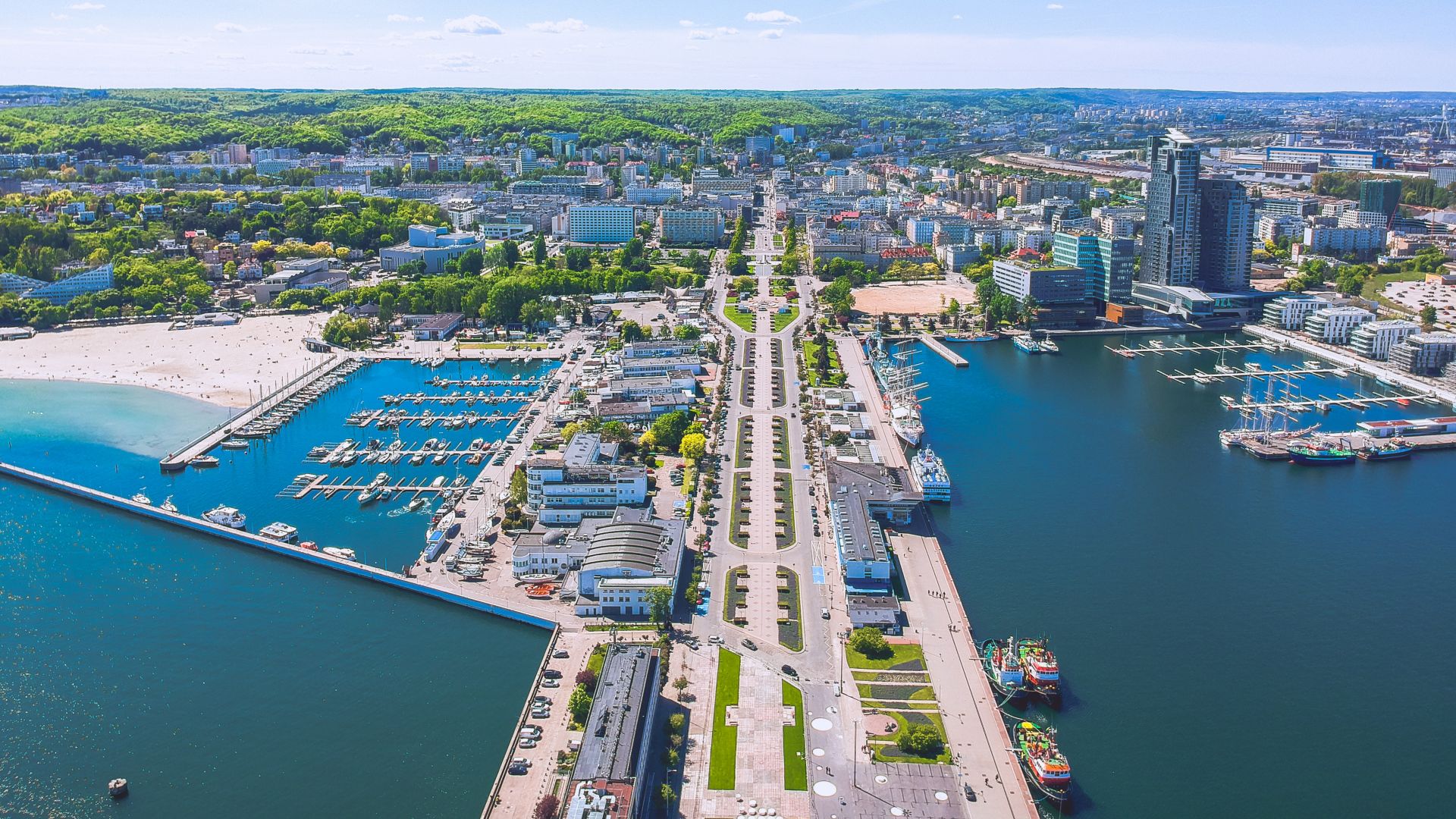 Flygfoto med utsikt från havet tillbaka över hamnen, stränderna och byggnaderna i Gdynia.