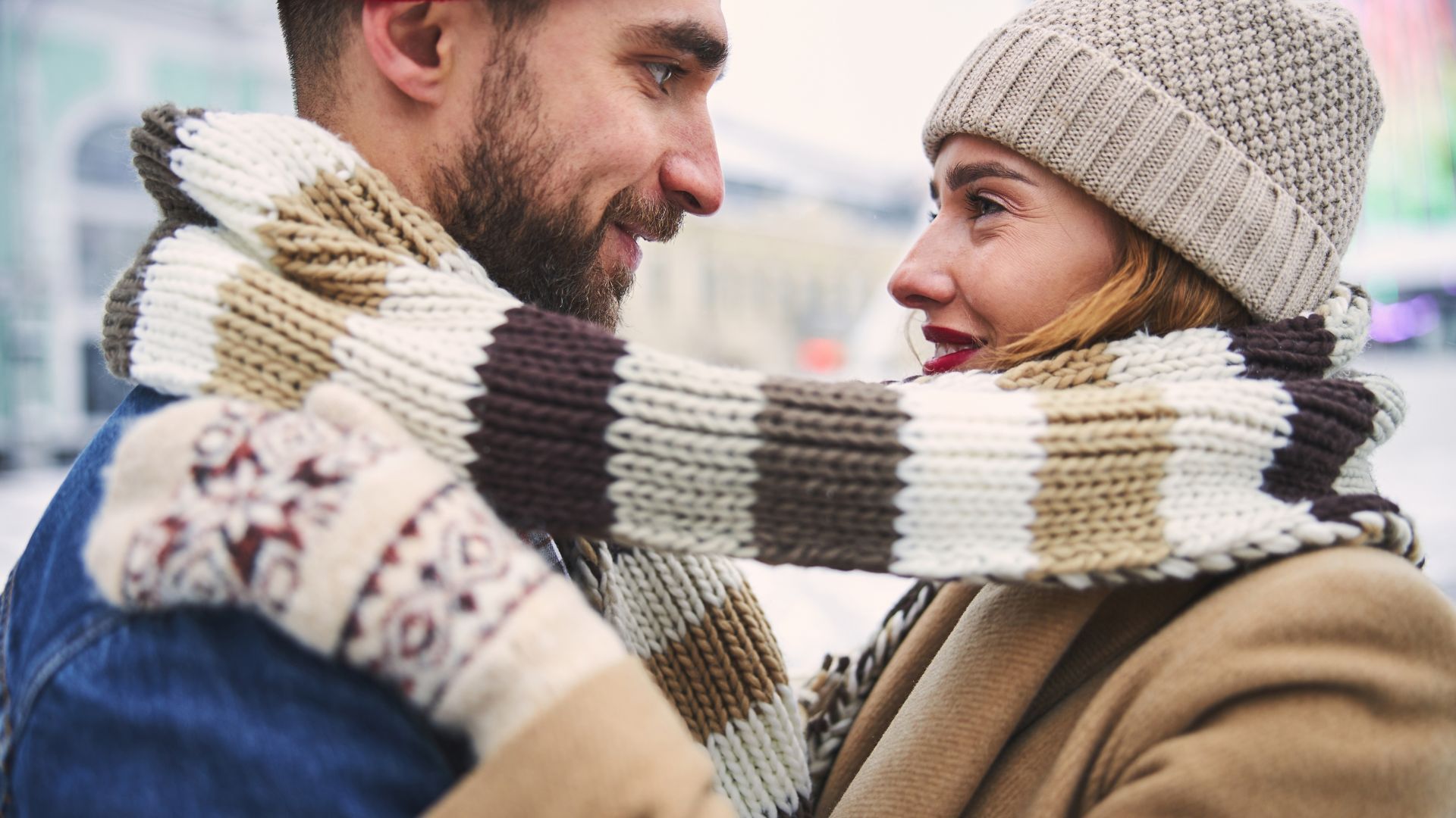 Profile cropped head portrait of young man and woman embracing and looking at each other outdoors