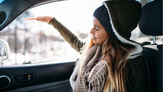 Happy young woman enjoying in car during winter