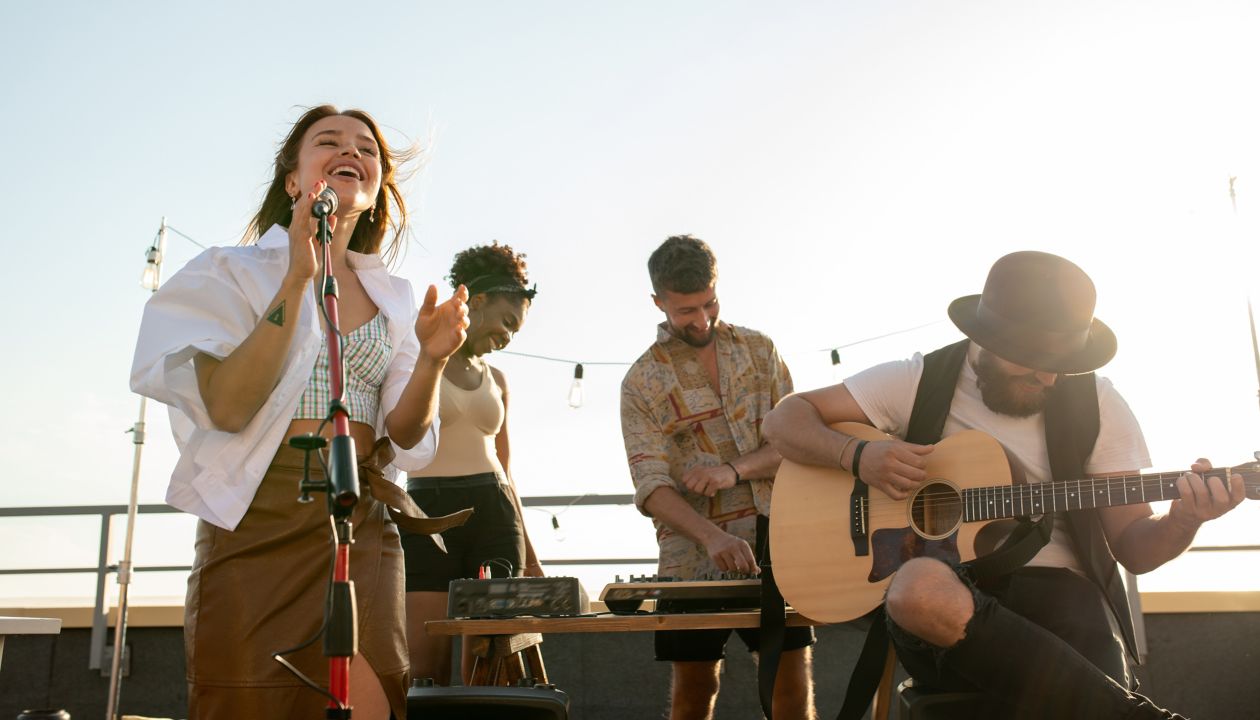 Moderne musikband med sanger og guitarist, der spiller ved fest på tagterrasse eller ved koncert