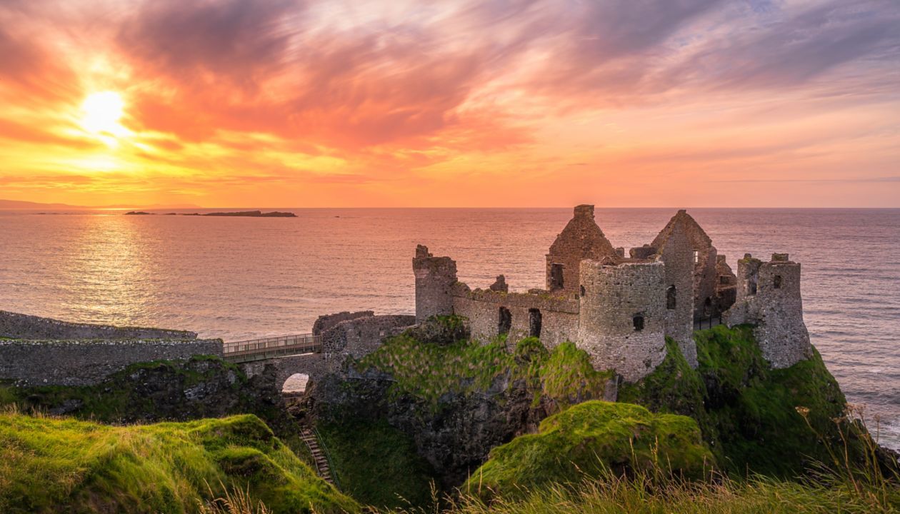 Ruined medieval Dunluce Castle on the cliff in Bushmills, Northern Ireland at sunset. Filming location of popular TV series