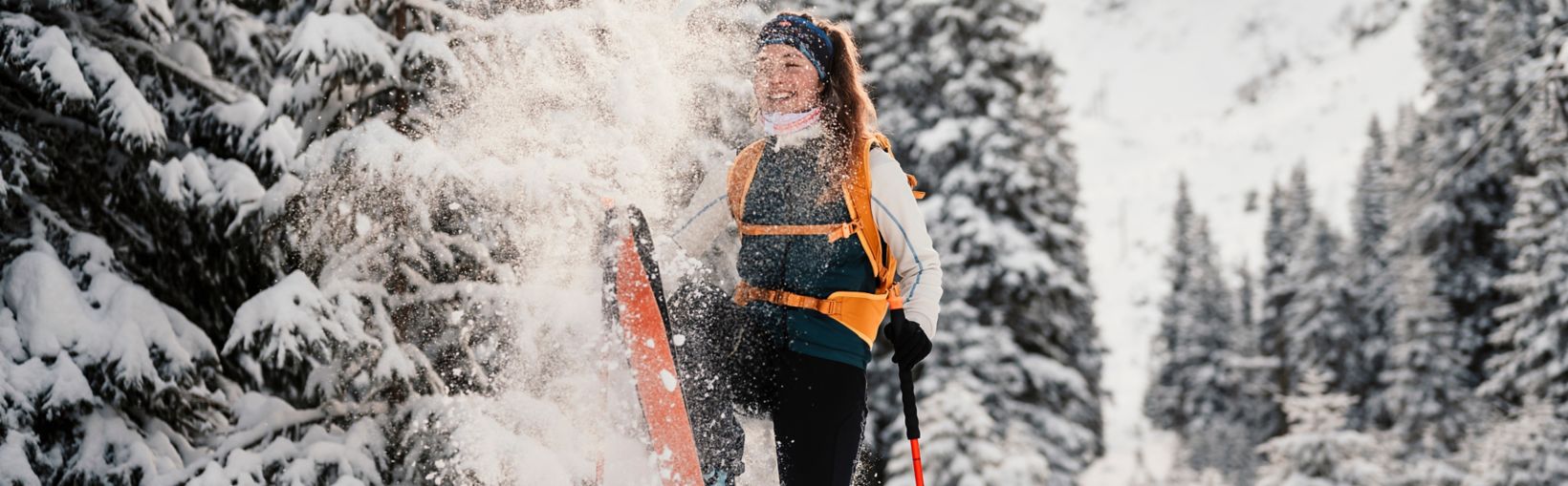 Mountaineer backcountry ski walking ski alpinist in the mountains. Ski touring in alpine landscape with snowy trees. Adventure winter sport.