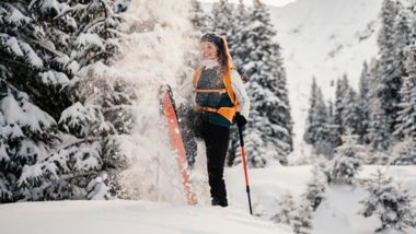 Mountaineer backcountry ski walking ski alpinist in the mountains. Ski touring in alpine landscape with snowy trees. Adventure winter sport.