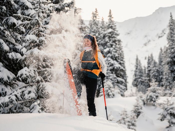 Mountaineer backcountry ski walking ski alpinist in the mountains. Ski touring in alpine landscape with snowy trees. Adventure winter sport.