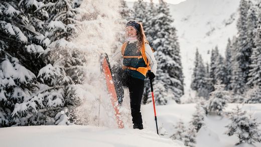 Mountaineer backcountry ski walking ski alpinist in the mountains. Ski touring in alpine landscape with snowy trees. Adventure winter sport.