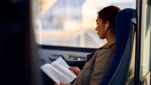 Young female passenger reads book while traveling by train.