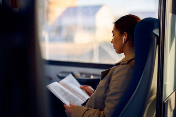 Young female passenger reads book while traveling by train.