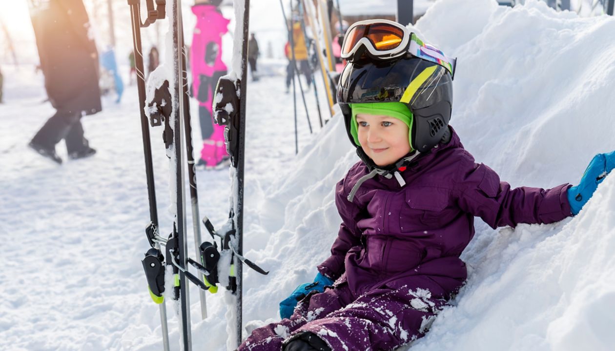 Cute adorable little kid boy enjoy having fun sledging down hill of snow heap snowdrift at alpine mountain skiing resort on bright winter day. Toddler beginner skier rest of training in ski school.