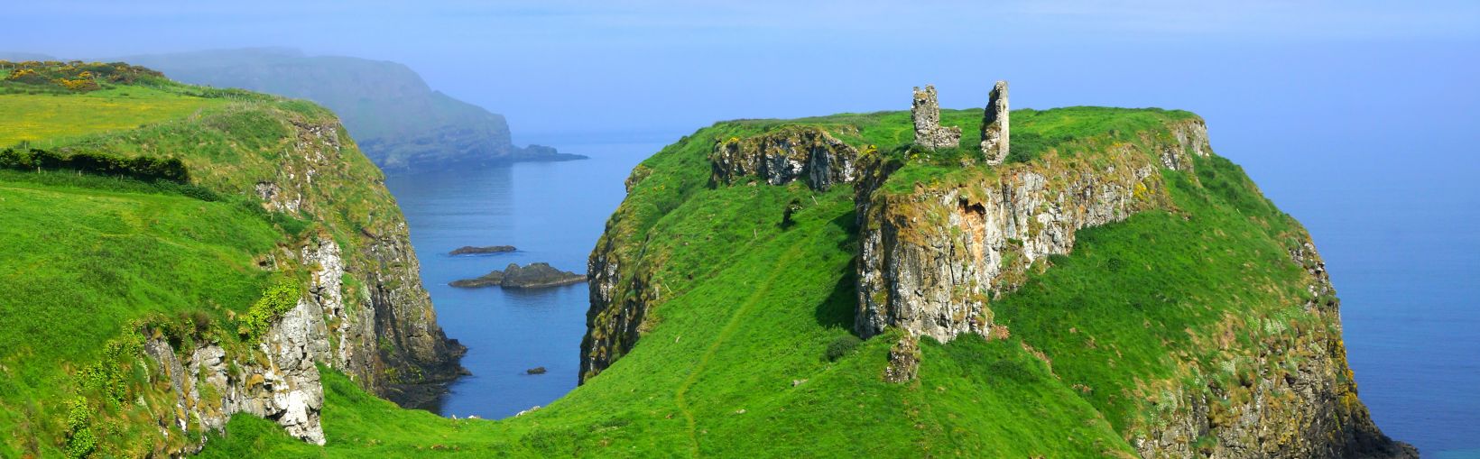 Ruiny starożytnego zamku Dunseverick na szczycie zielonych klifów wybrzeża Causeway, Irlandia Północna