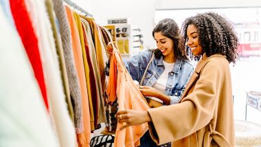Happy young multiracial friends shopping together at clothing store