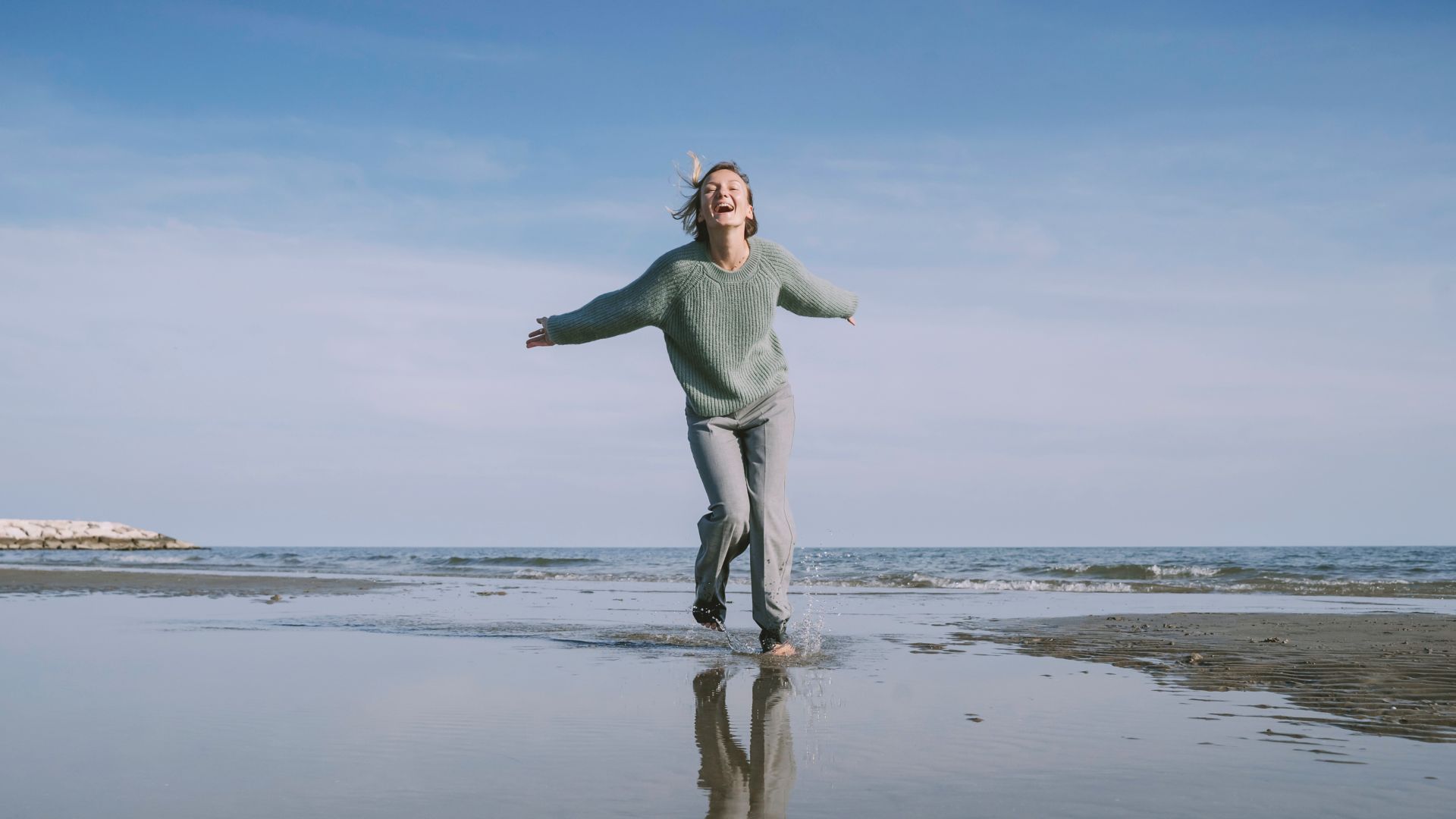 Onnellinen nainen juoksee rannalla