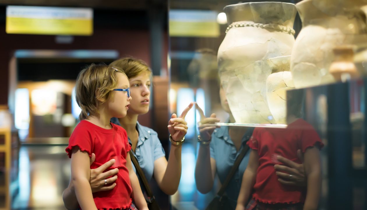 mor och barn som tittar på antika amforor på ett museum