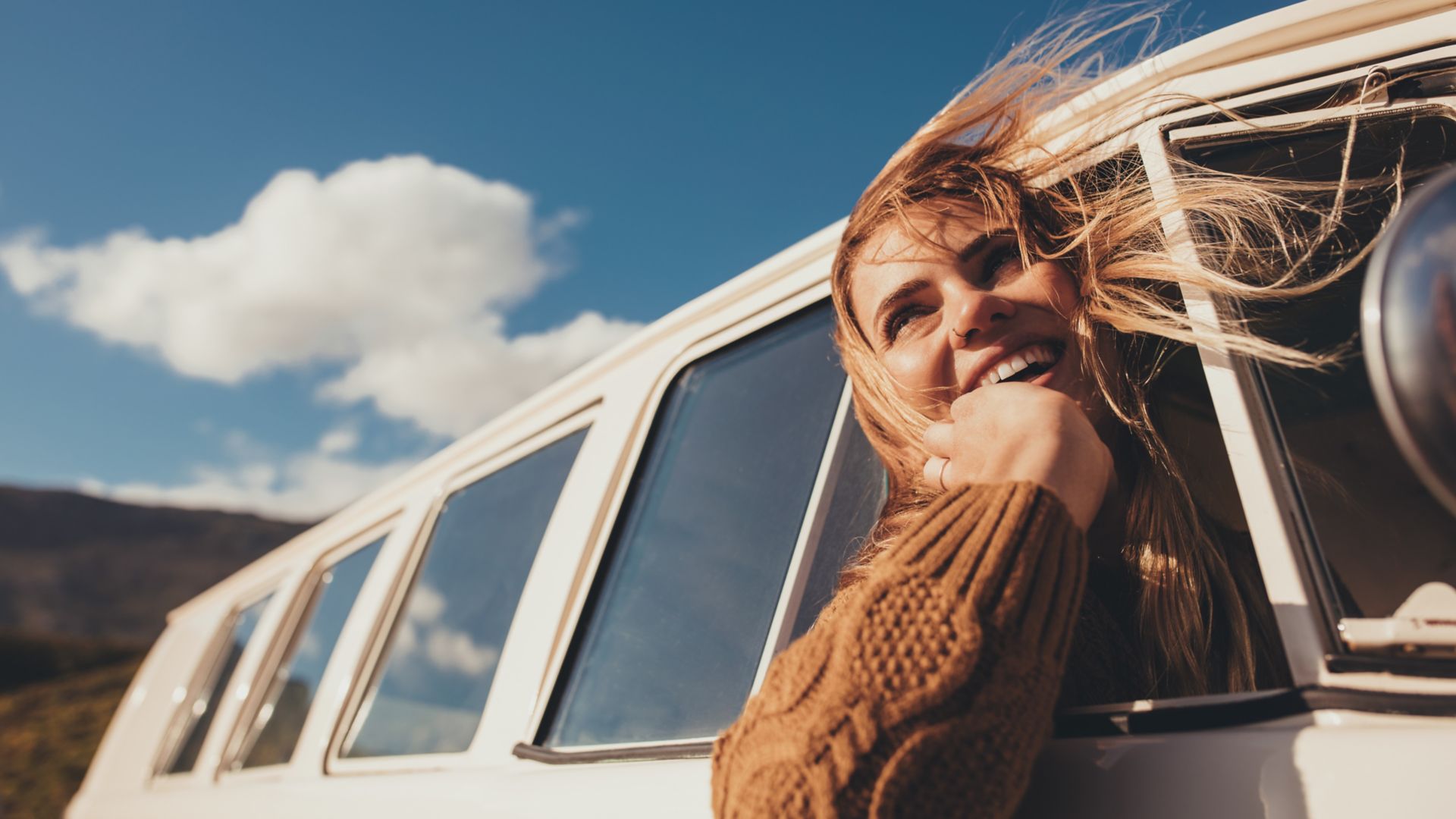 Woman driving a van and enjoying road trip. Laughing young female having fun on her vacation.