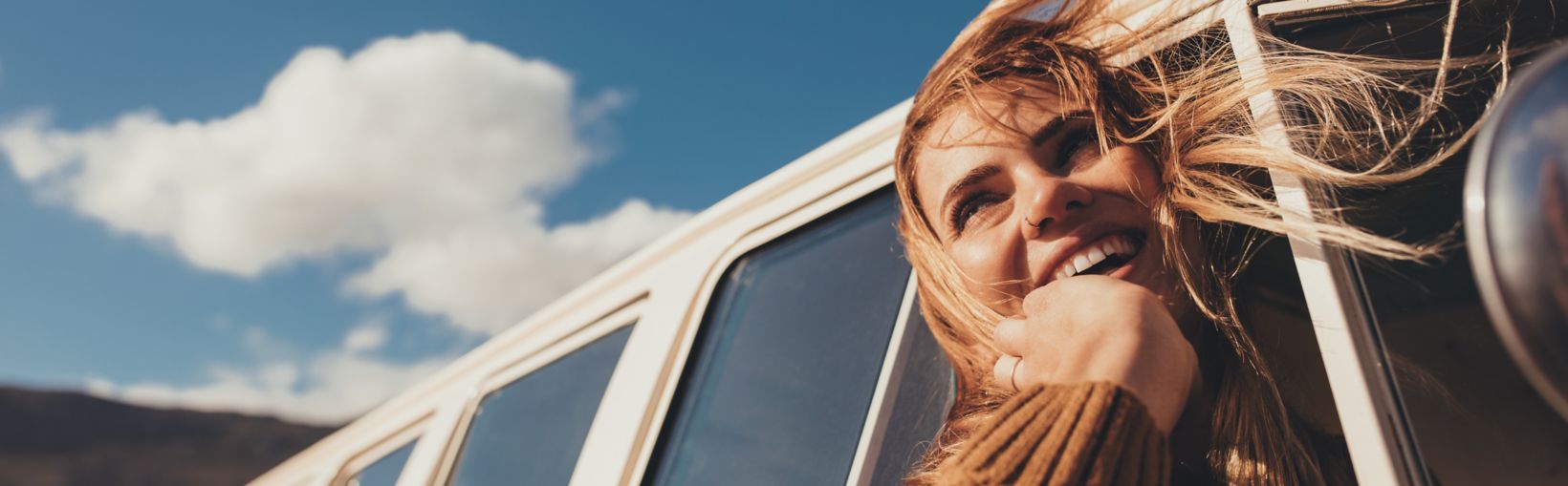 Woman driving a van and enjoying road trip. Laughing young female having fun on her vacation.