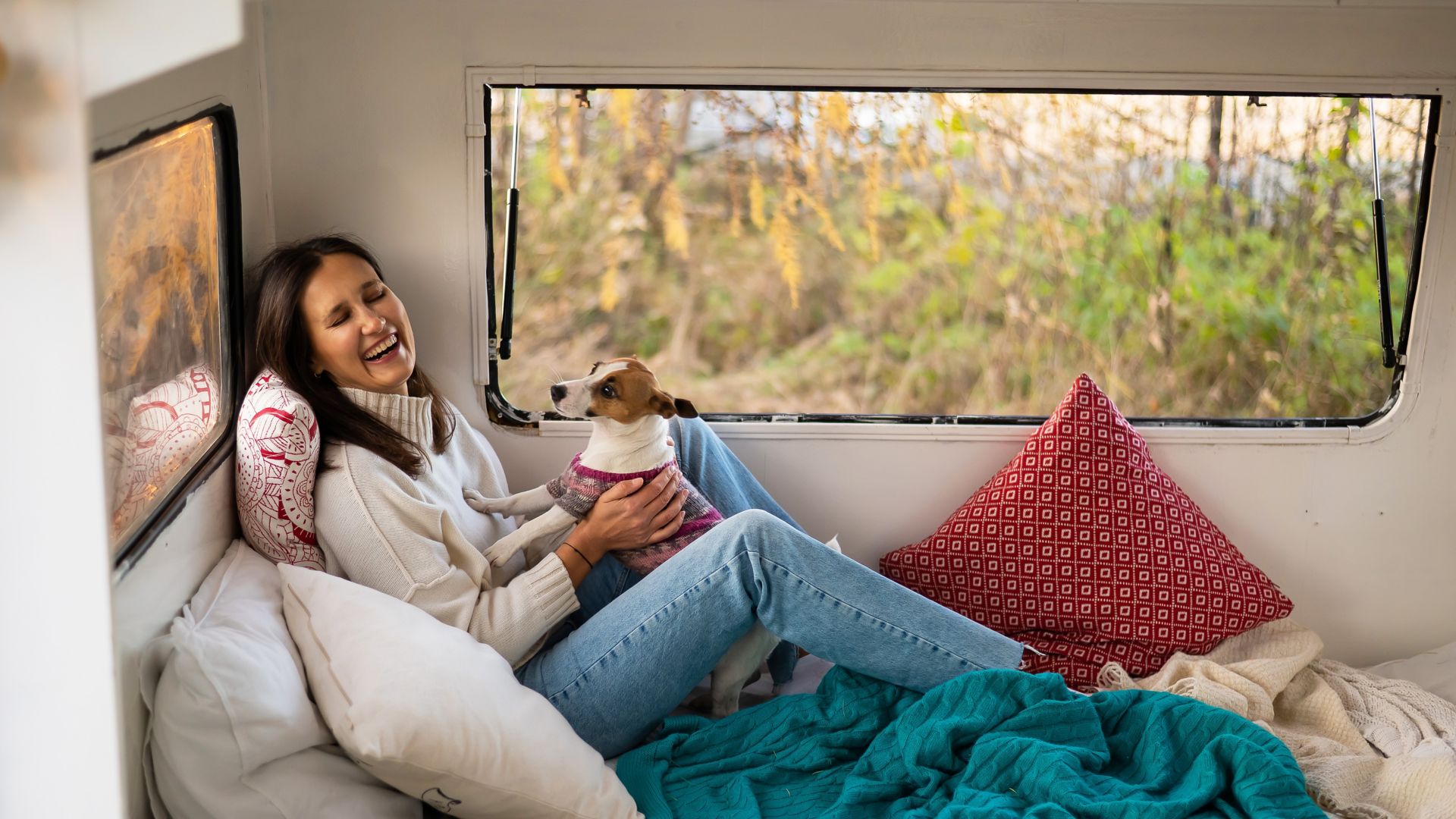 Woman relaxing with her dog in a cosy caravan, enjoying a calm travel moment