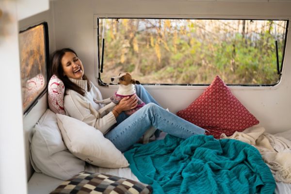 Caucasian woman sitting in a van hugging with dog Jack Russell Terrier. Travel in a camper in the fall