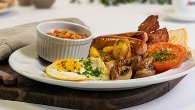 Full frokost med pølser, bacon, speilegg, bønner, hash browns og toast