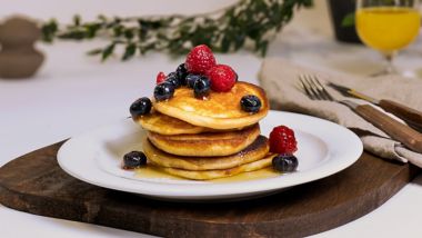 Stack of pancakes topped with berries and syrup