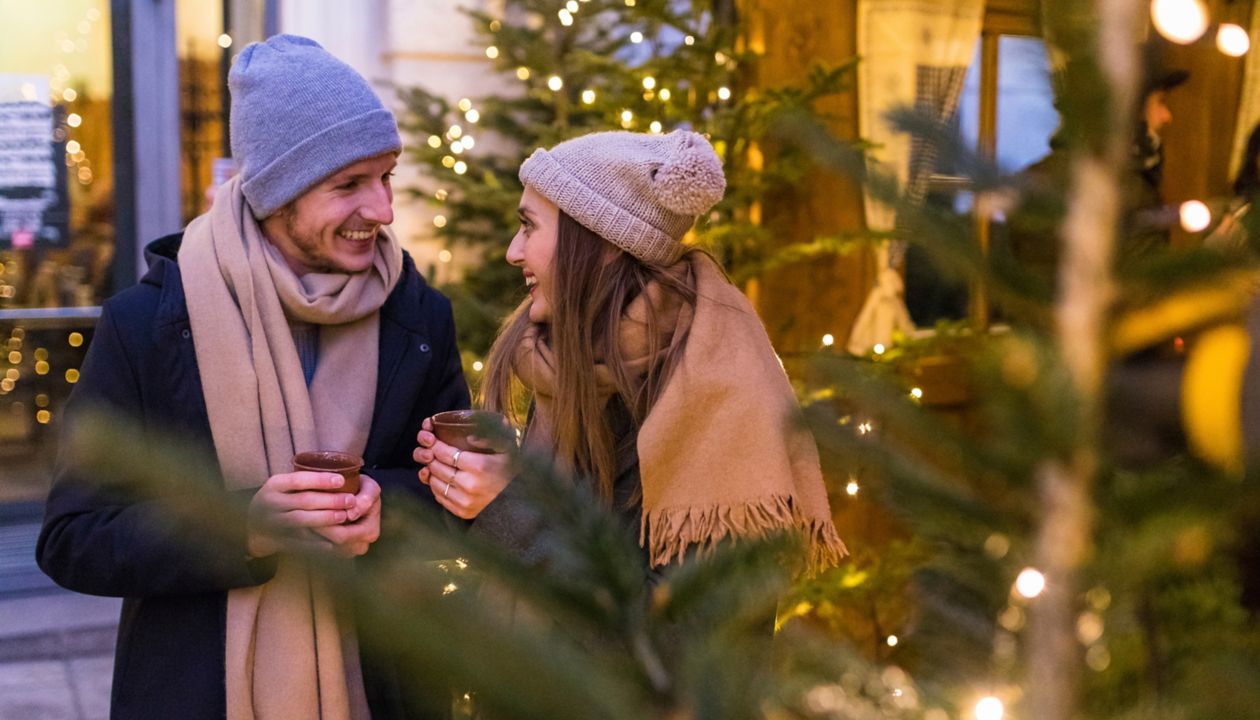 Happy young couple drinking mulled wine at Christmas market