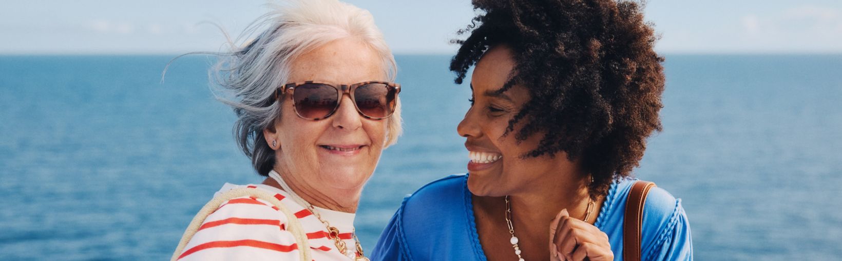 Twee vrouwen lachen samen op het buitendek van een Stena Line veerboot en genieten van een zonnige overtocht