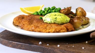 Crispy pork schnitzel with roasted potatoes, peas and herb butter