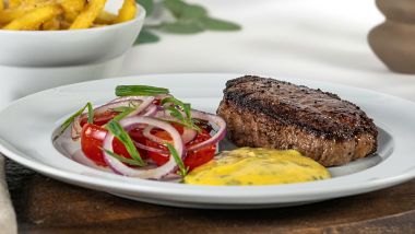 Grilled steak with fries, tomato and red onion salad, served with creamy sauce