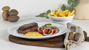 Grilled steak with fries, tomato and red onion salad, served with creamy sauce