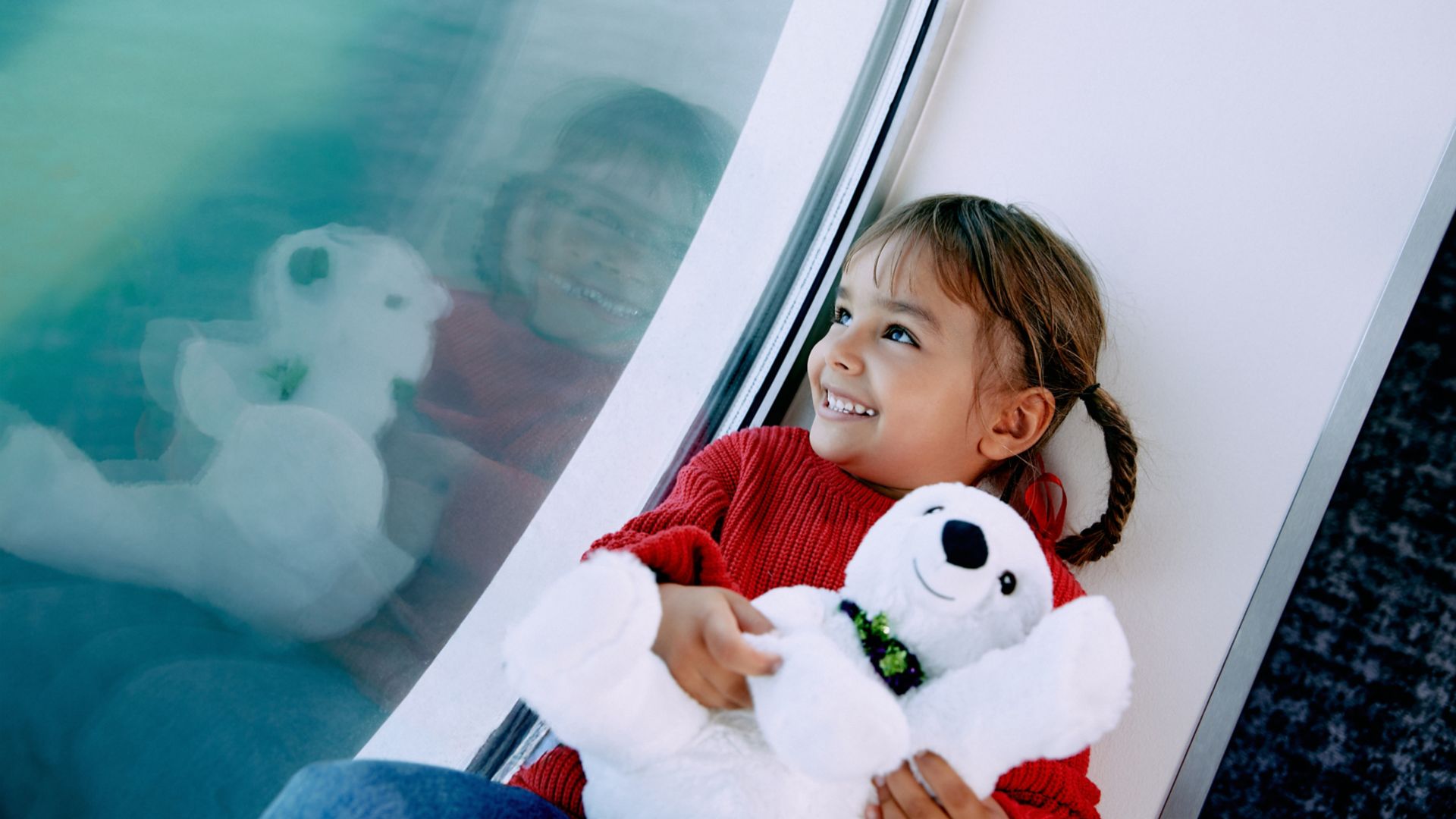 Leende barn kramar nalle och tittar ut mot havet från Stena Lines färjesalong