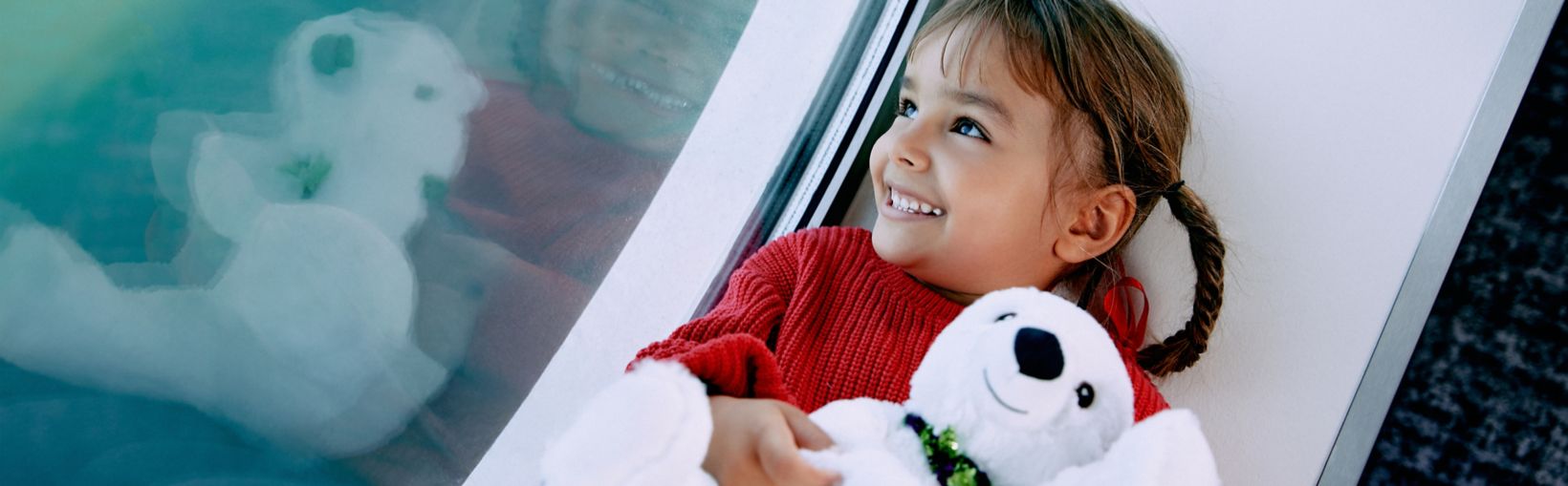 Leende barn kramar nalle och tittar ut mot havet från Stena Lines färjesalong