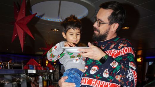 Man and child in Christmas sweaters enjoying food at a Christmas buffet at Stenline
