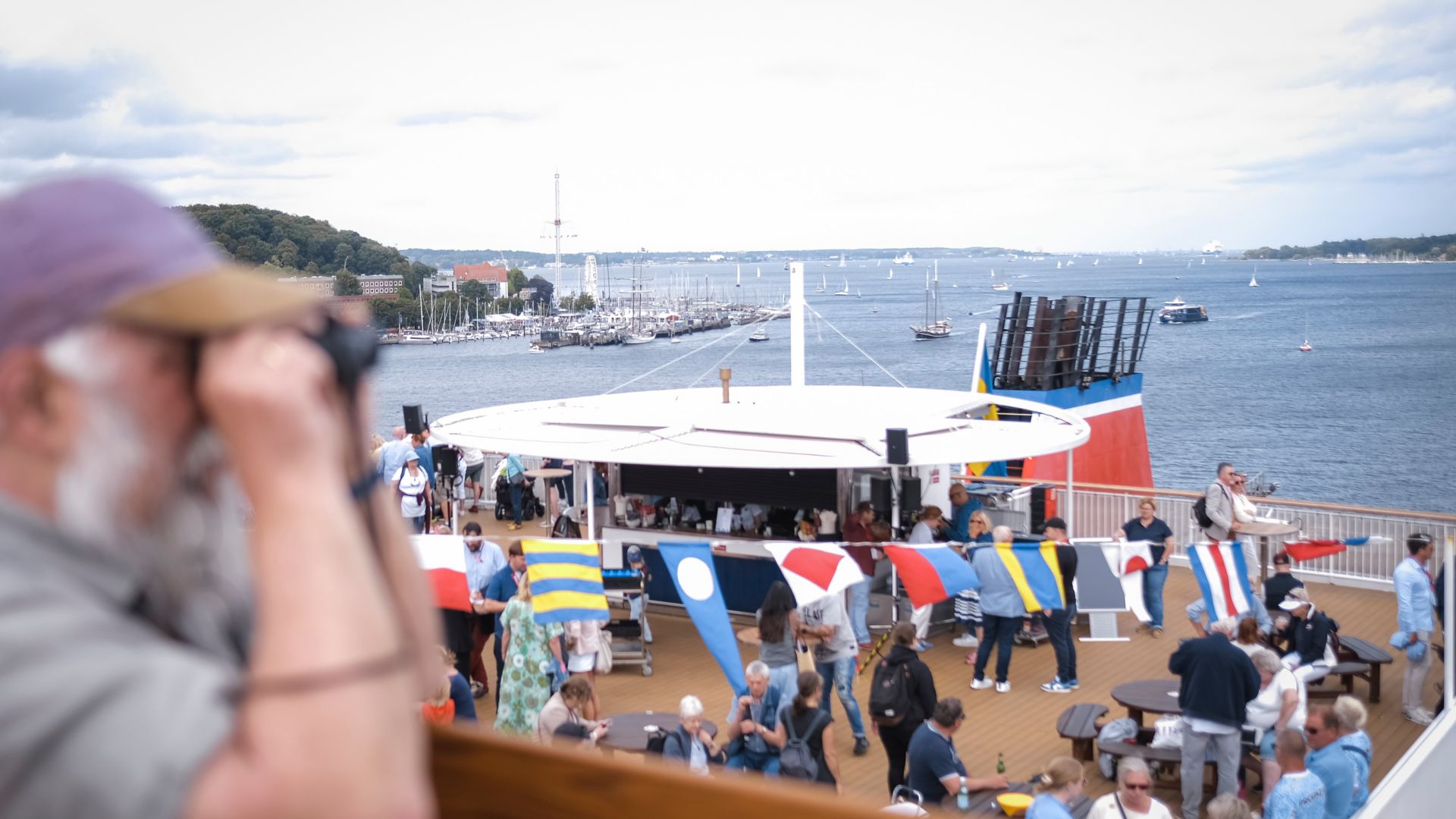 Passagiere geniessen die Kieler Woche auf dem Sonnendeck der Stena Germanica mit maritimen Flaggen und Blick über den Kieler Hafen