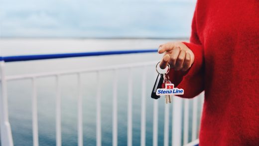 Close-up of a woman holding car keys with a Stena Line keyring on the outer deck of a ferry