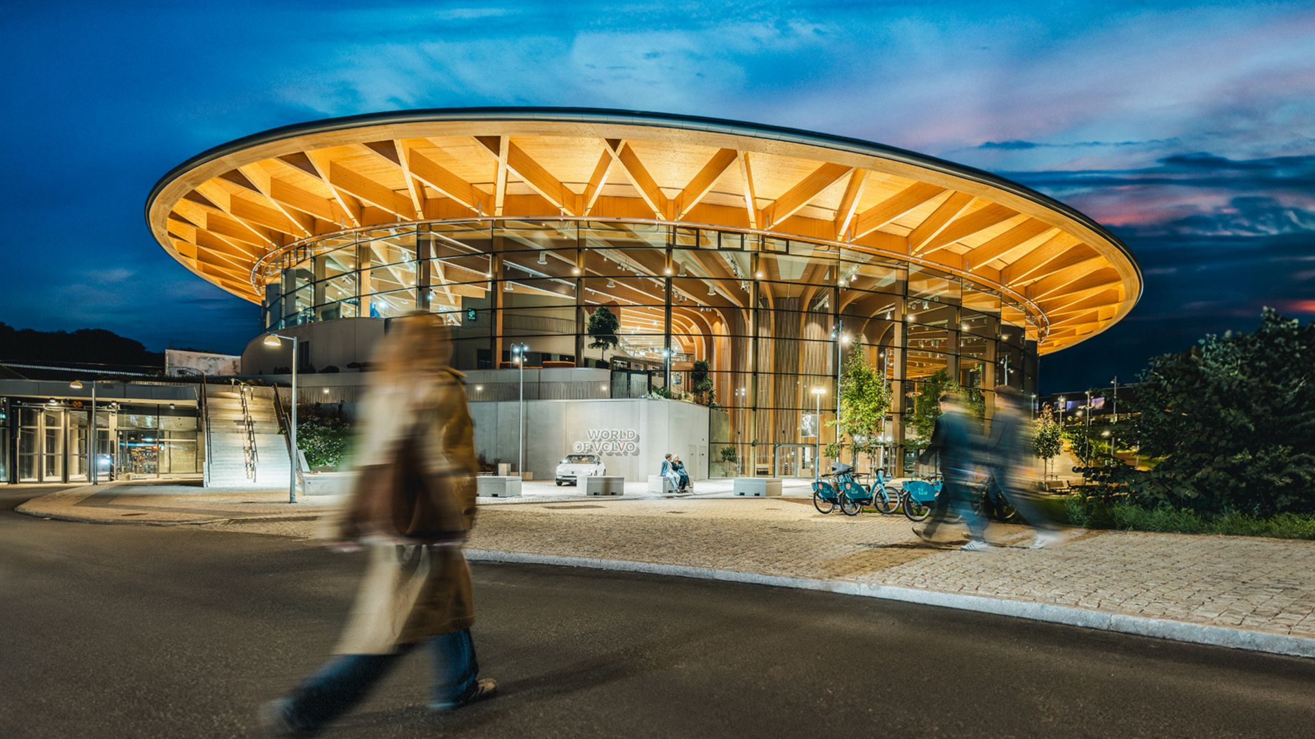 Ein modernes, architektonisch gestaltetes Gebäude mit großen Glasfenstern und einem geschwungenen Holzdach.