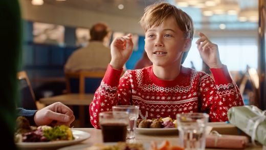 Kid enjoying Christmas buffet onboard ferry in festive jumpers during their holiday crossing