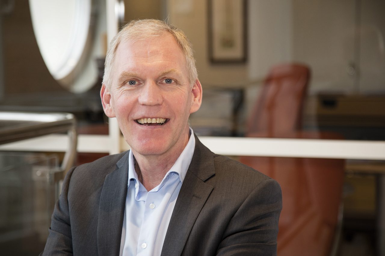 man ler mot kameran i bankmiljo