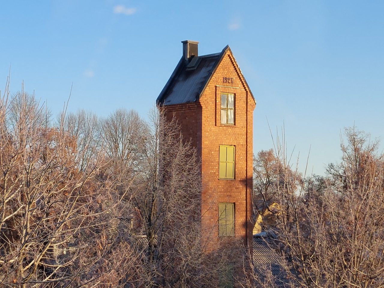 Gammal tegelbyggnad från 1926. Framför är kala träd.