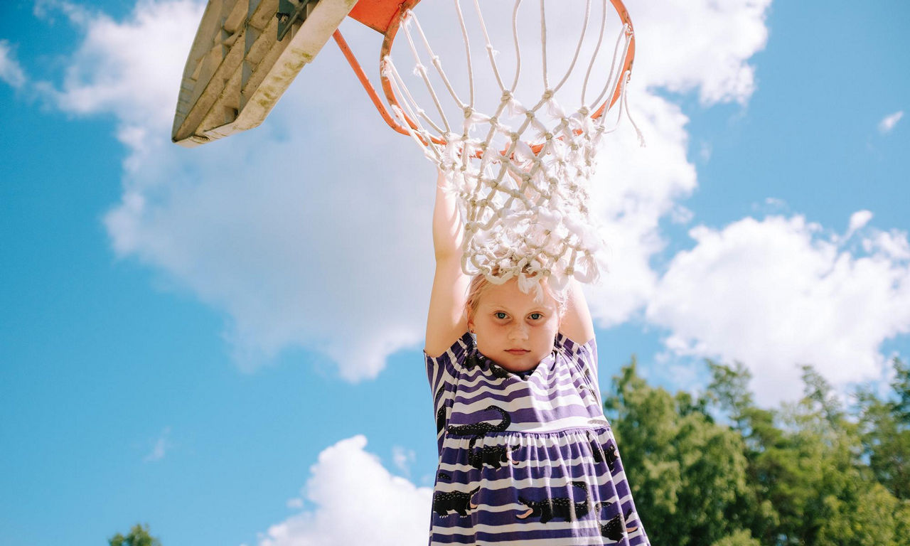 Tjej hänger i basketkorg